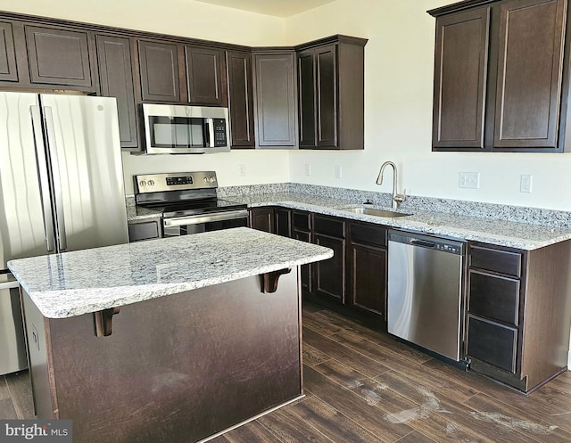 kitchen with a breakfast bar, stainless steel appliances, dark wood-type flooring, a sink, and dark brown cabinets