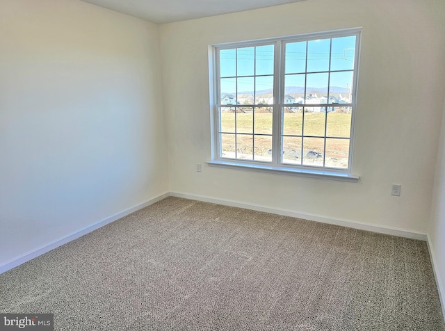 carpeted spare room featuring baseboards