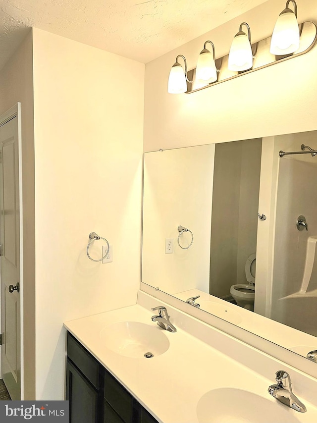 bathroom featuring a textured ceiling, double vanity, and a sink