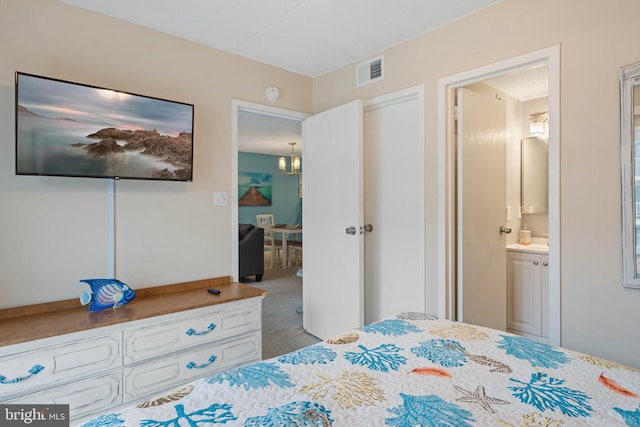 carpeted bedroom with ensuite bath and a chandelier