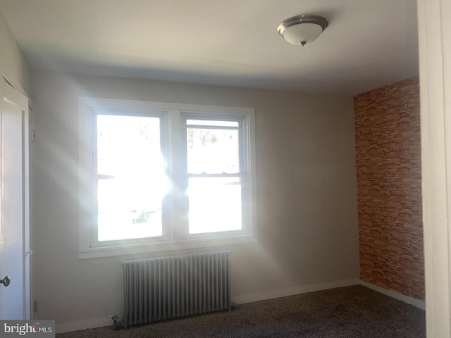 unfurnished room featuring carpet floors, radiator heating unit, and a wealth of natural light