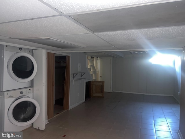 clothes washing area featuring tile flooring and stacked washer and clothes dryer