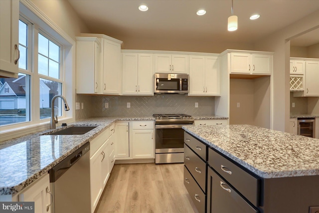 kitchen featuring wine cooler, light wood-style flooring, a sink, white cabinetry, and appliances with stainless steel finishes