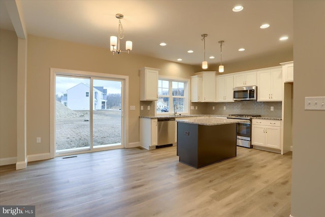 kitchen featuring stainless steel appliances, white cabinets, backsplash, and light wood finished floors