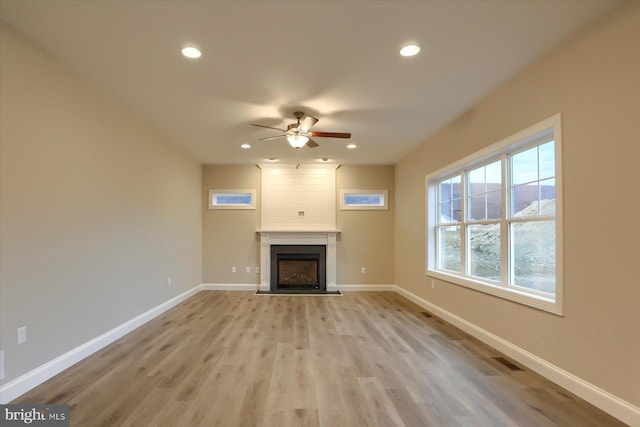 unfurnished living room featuring a large fireplace, light wood-style flooring, baseboards, and recessed lighting