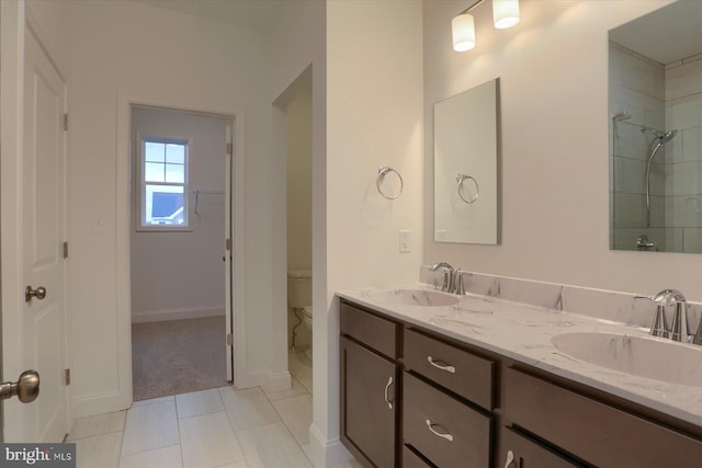 bathroom with double vanity, a sink, toilet, and tile patterned floors