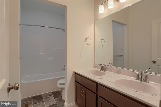 bathroom with toilet, double vanity, a sink, and shower / bathing tub combination