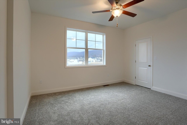 carpeted spare room with a ceiling fan, visible vents, and baseboards