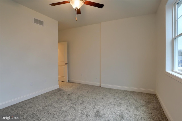 unfurnished room featuring light carpet, a ceiling fan, visible vents, and baseboards