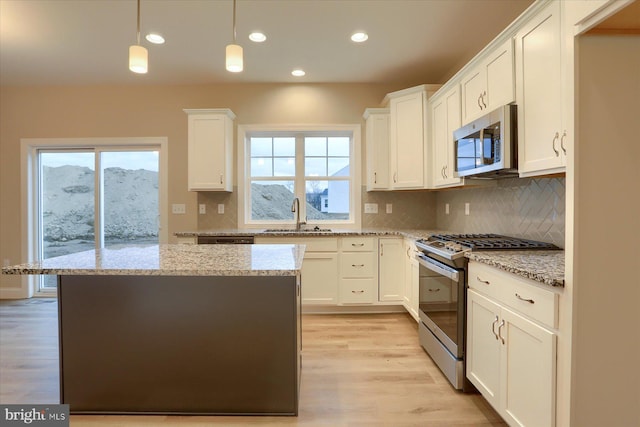 kitchen featuring stainless steel appliances, plenty of natural light, a sink, and light wood-style floors