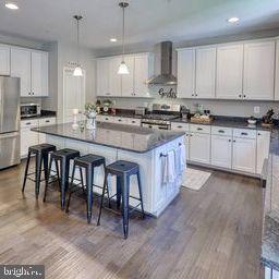 kitchen featuring white cabinetry and wall chimney range hood