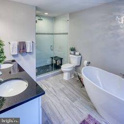 full bathroom with separate shower and tub, vanity, wood-type flooring, and toilet