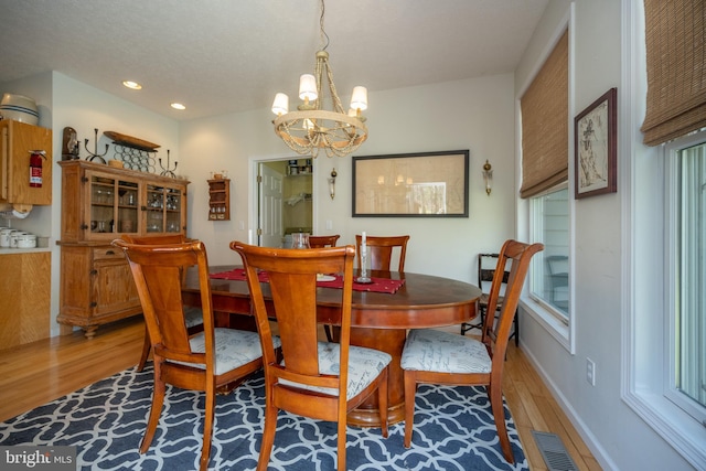 dining space with hardwood / wood-style floors and a notable chandelier