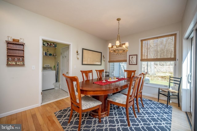 dining area featuring a notable chandelier, light hardwood / wood-style flooring, and washer / dryer