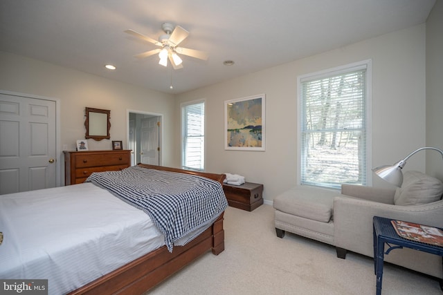 bedroom featuring light colored carpet, ceiling fan, and multiple windows