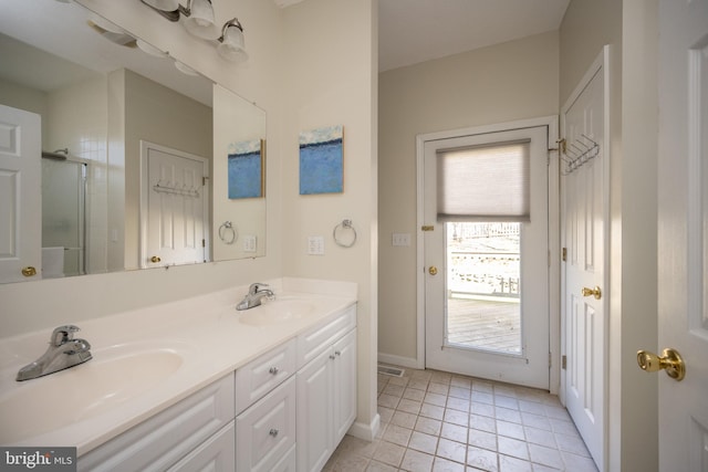 bathroom with double sink, tile floors, vanity with extensive cabinet space, and a wealth of natural light