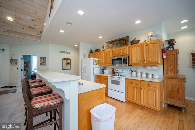 kitchen with white appliances, a kitchen bar, light carpet, a center island, and wooden ceiling