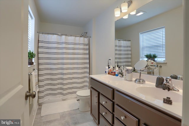 bathroom with tile patterned floors, vanity, toilet, and curtained shower