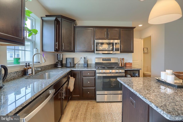 kitchen featuring sink, light hardwood / wood-style flooring, appliances with stainless steel finishes, dark brown cabinets, and light stone counters