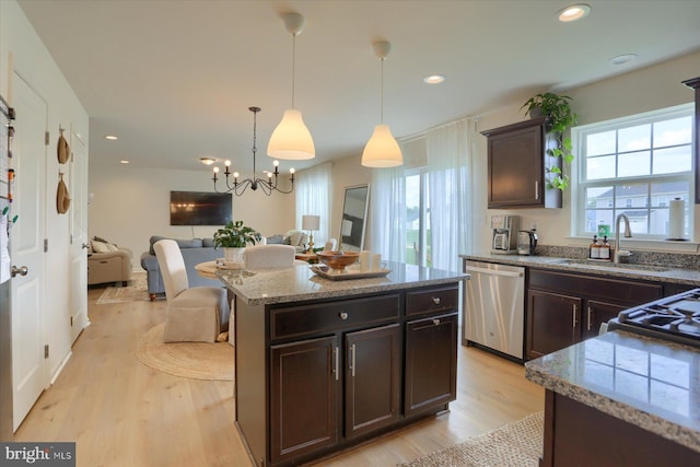 kitchen featuring sink, light hardwood / wood-style flooring, pendant lighting, a kitchen island, and appliances with stainless steel finishes