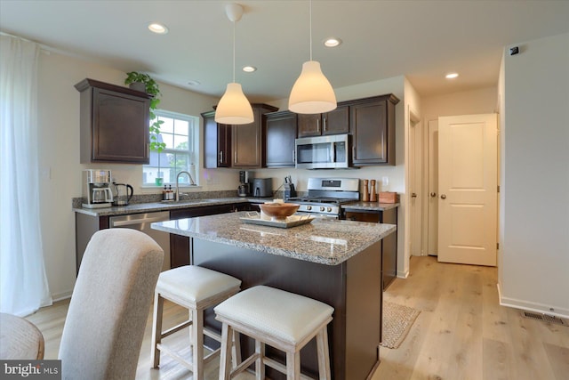 kitchen featuring dark brown cabinetry, sink, a center island, appliances with stainless steel finishes, and light wood-type flooring