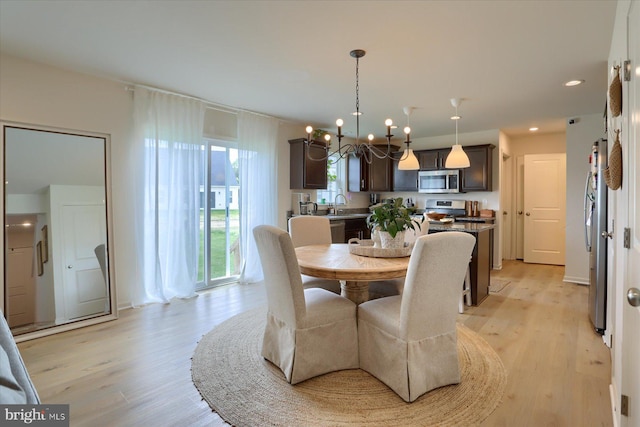 dining area with a wealth of natural light, light hardwood / wood-style floors, and an inviting chandelier