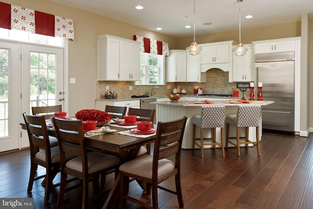 interior space with stainless steel built in fridge, a center island, decorative light fixtures, backsplash, and dark hardwood / wood-style floors