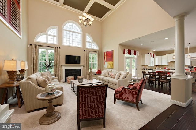 living room featuring hardwood / wood-style floors, a chandelier, ornate columns, and a healthy amount of sunlight