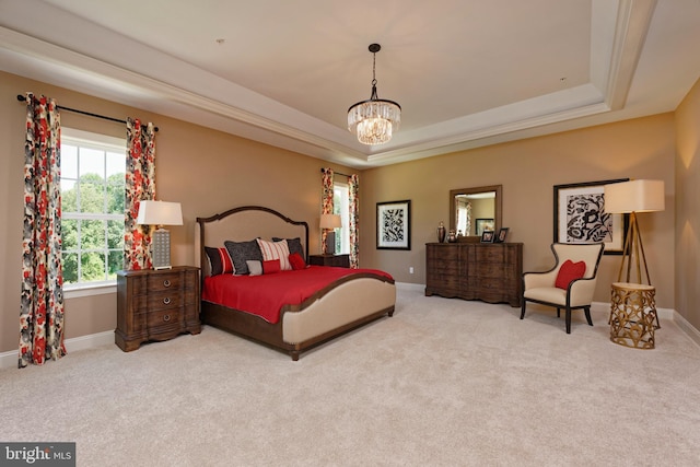 bedroom with an inviting chandelier, a tray ceiling, and light colored carpet