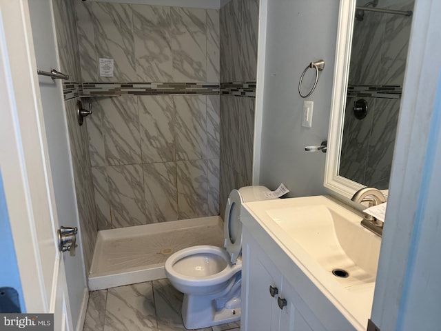 bathroom featuring a tile shower, tile flooring, vanity with extensive cabinet space, and toilet