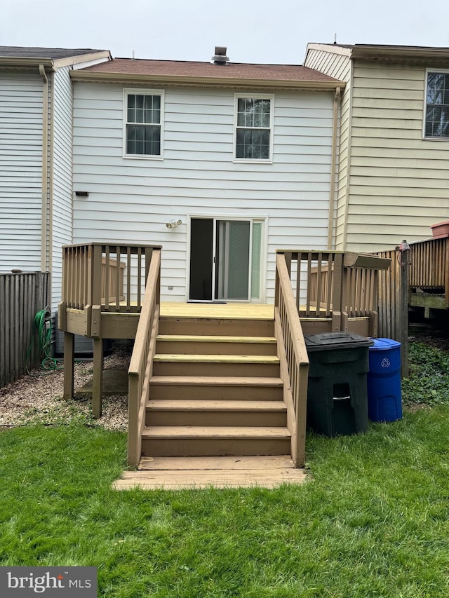 back of property with a wooden deck and a lawn