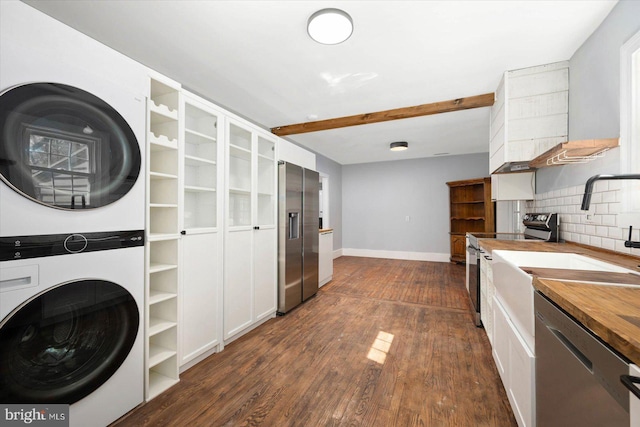 kitchen featuring butcher block countertops, stacked washer / dryer, appliances with stainless steel finishes, white cabinetry, and dark hardwood / wood-style floors