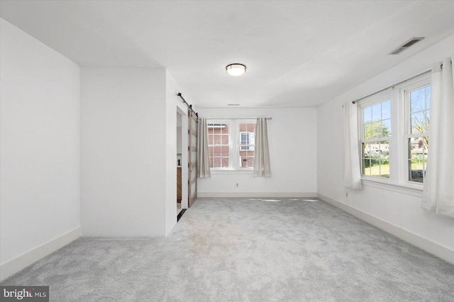 carpeted spare room with a barn door and a healthy amount of sunlight