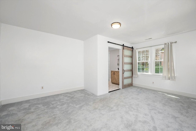 unfurnished bedroom featuring a barn door and light carpet