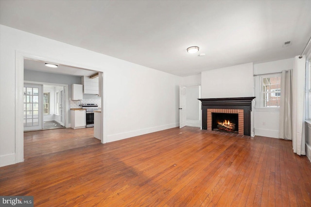 unfurnished living room with a brick fireplace and wood-type flooring