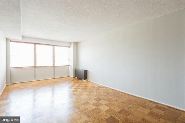 unfurnished room with light parquet floors and a textured ceiling