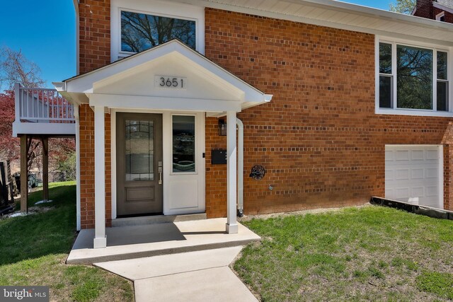 view of exterior entry featuring a garage and a lawn