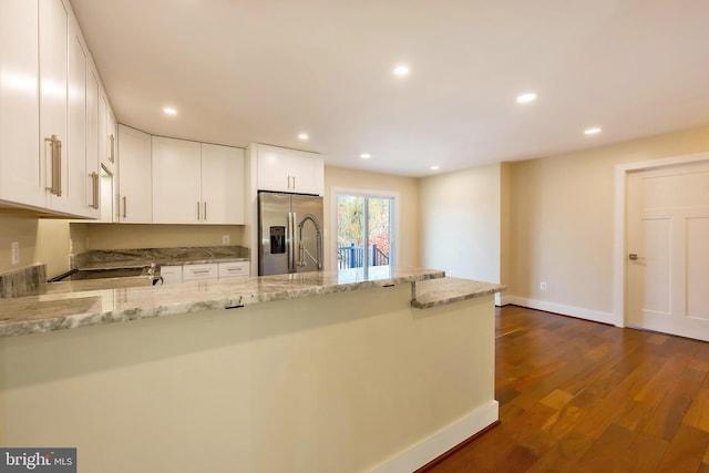 kitchen with white cabinets, dark hardwood / wood-style flooring, stainless steel fridge, and light stone countertops