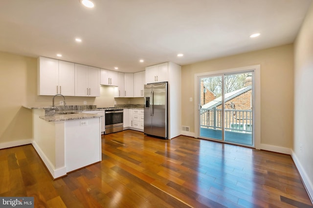 kitchen with white cabinetry, appliances with stainless steel finishes, dark hardwood / wood-style floors, light stone counters, and sink