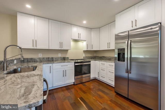 kitchen featuring white cabinets, light stone countertops, dark hardwood / wood-style flooring, appliances with stainless steel finishes, and sink