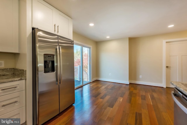 kitchen featuring appliances with stainless steel finishes, dark wood-type flooring, white cabinets, and light stone counters