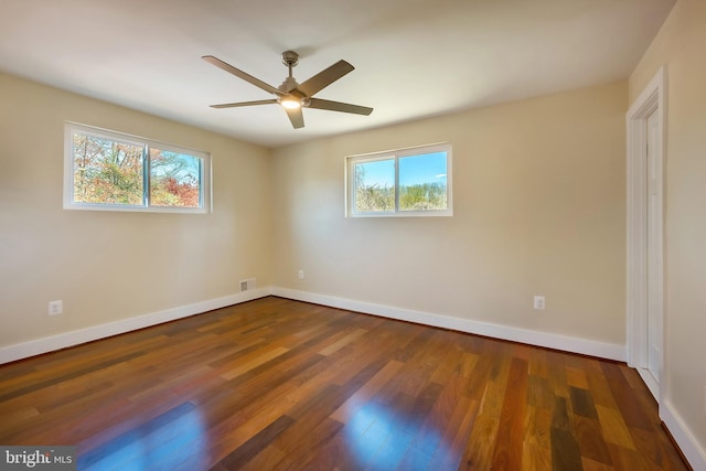 unfurnished room featuring a healthy amount of sunlight, dark hardwood / wood-style floors, and ceiling fan