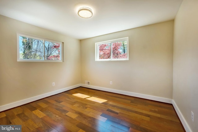 empty room with plenty of natural light and dark hardwood / wood-style floors