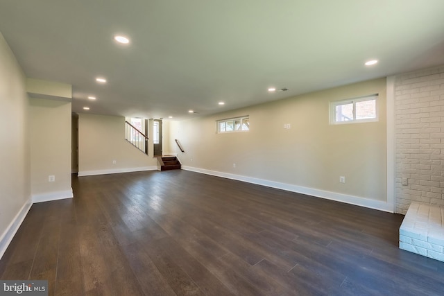 basement with dark wood-type flooring and brick wall