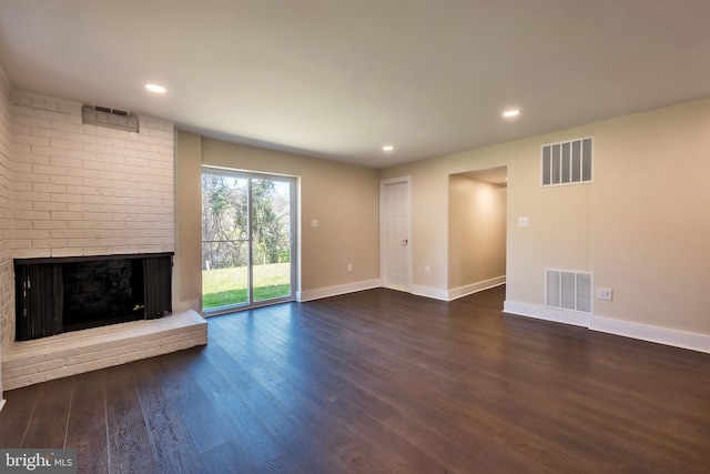 unfurnished living room featuring brick wall, dark hardwood / wood-style flooring, and a fireplace