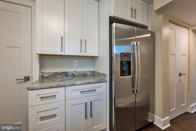 kitchen with white cabinetry, dark hardwood / wood-style floors, stainless steel fridge, and light stone countertops