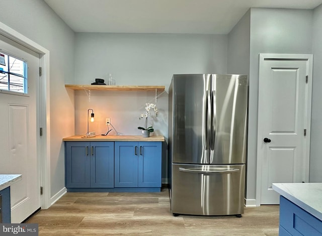 kitchen with light hardwood / wood-style flooring, stainless steel fridge, and blue cabinetry