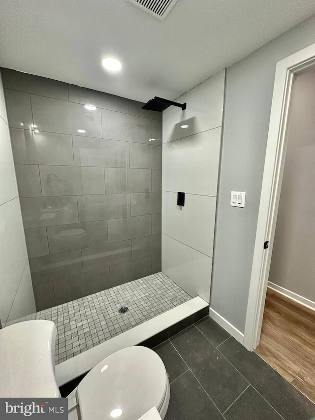 bathroom featuring tiled shower, toilet, and hardwood / wood-style floors