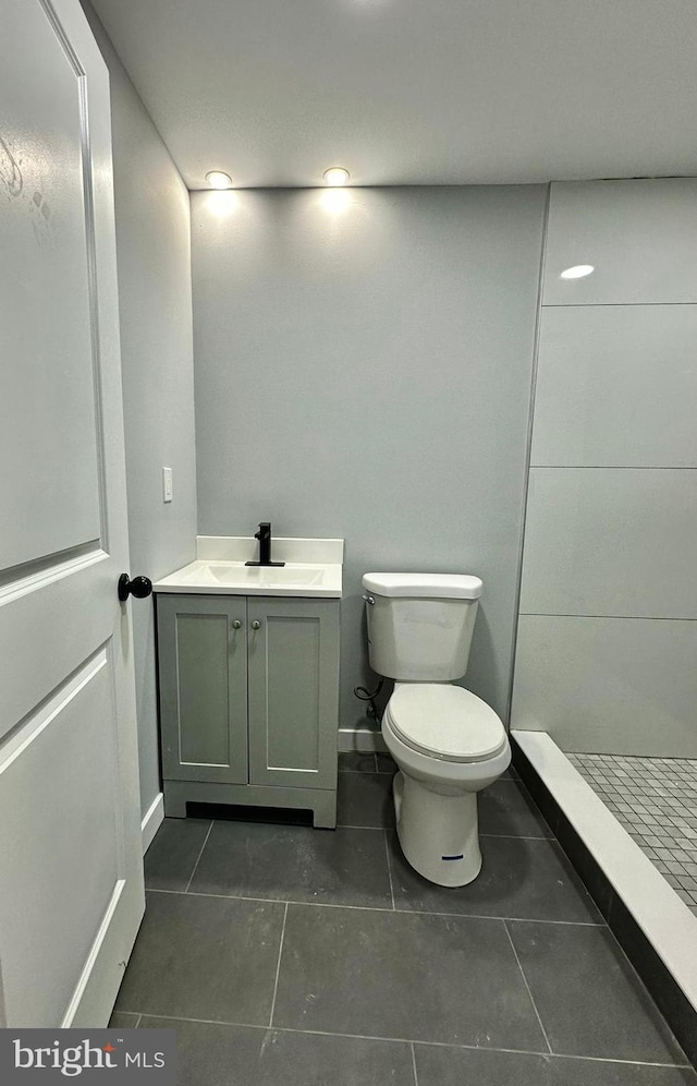 bathroom featuring walk in shower, vanity, toilet, and tile floors