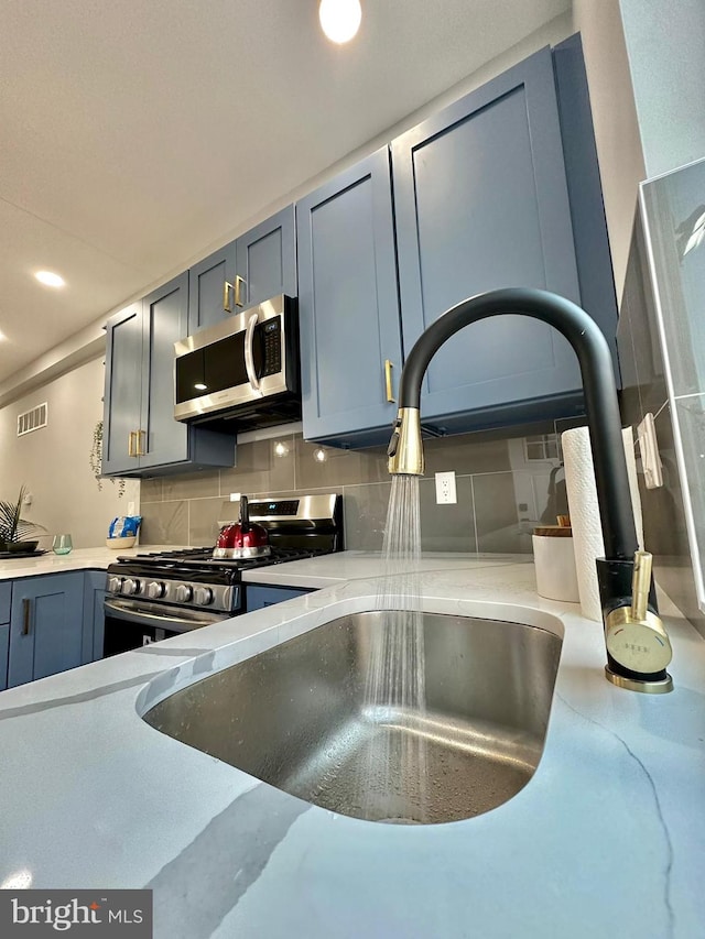 kitchen featuring backsplash, appliances with stainless steel finishes, and sink